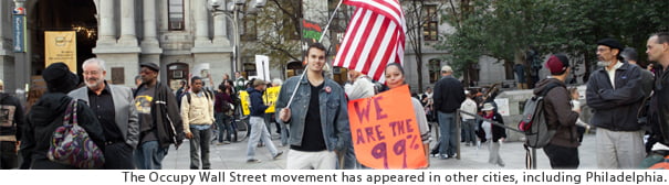 Occupy Wall Street protesters holding an American flag and a sign reading "We are the 99%"