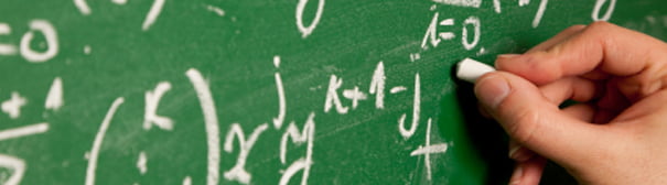 A hand writing complex formulas on a chalk board.